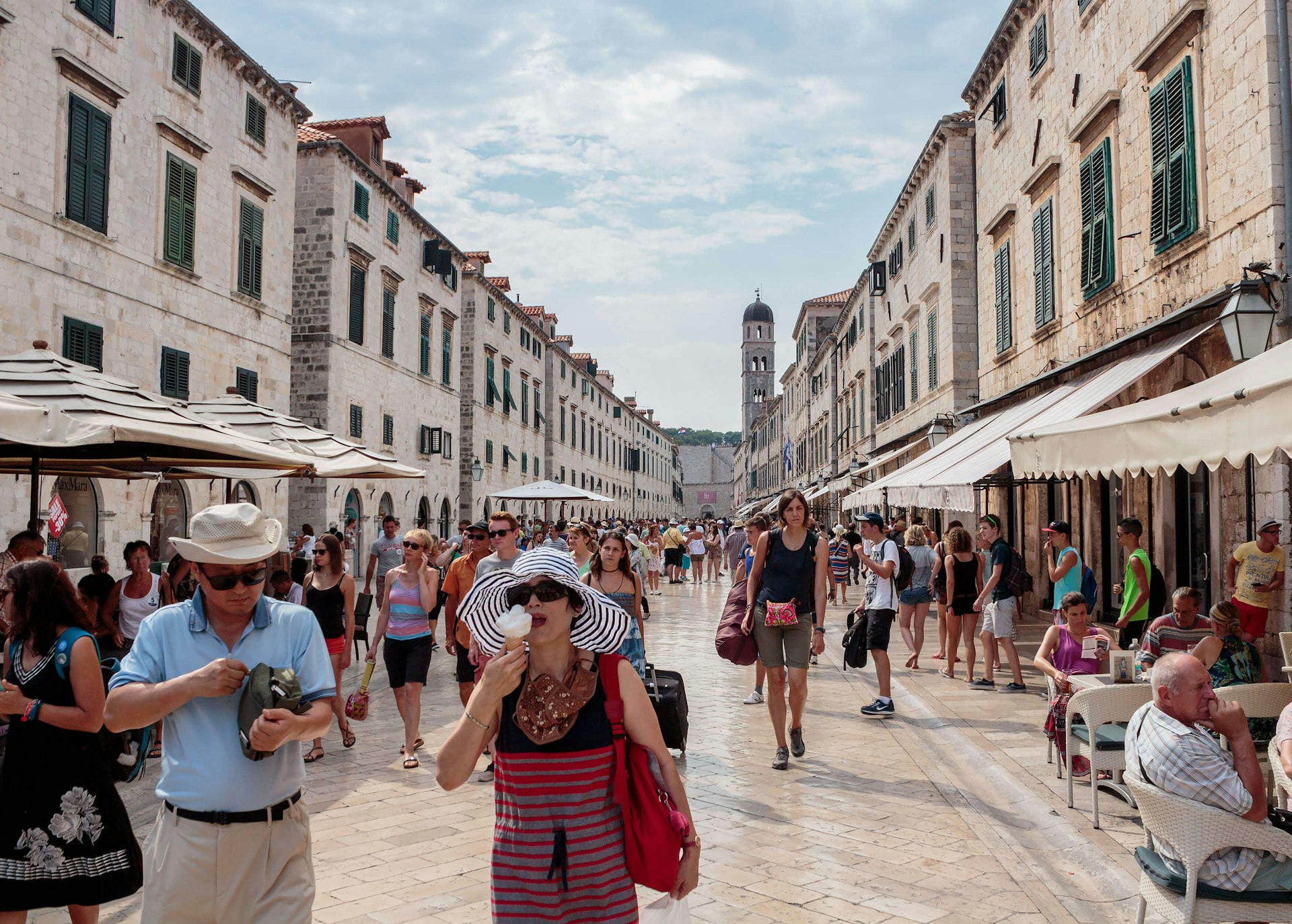 Summer scene of the main street (Stradun or Placa), with locals, tourists and a woman eating an ice cream cone