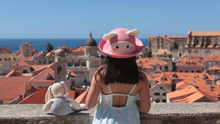 White girl with a cute bunny straw hat is enjoying beautiful scenery of old town Dubrovnik with her stuffed bunny