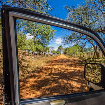 A dusty lane is seen through an open window of a car in the Dominican Republic.