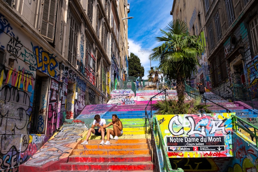 A young couple rests on the graffiti-decorated stairs of the Cours Julien, a lively neighborhood in central Marseille, near the Vieux Port.