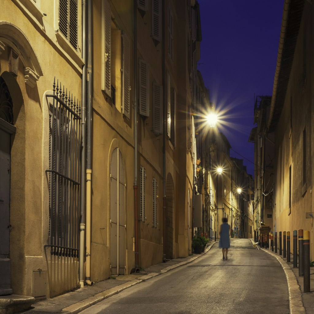 A person walking on a city street in the old Le Panier district of Marseille, France, in the evening.