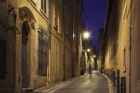 A person walking on a city street in the old Le Panier district of Marseille, France, in the evening.