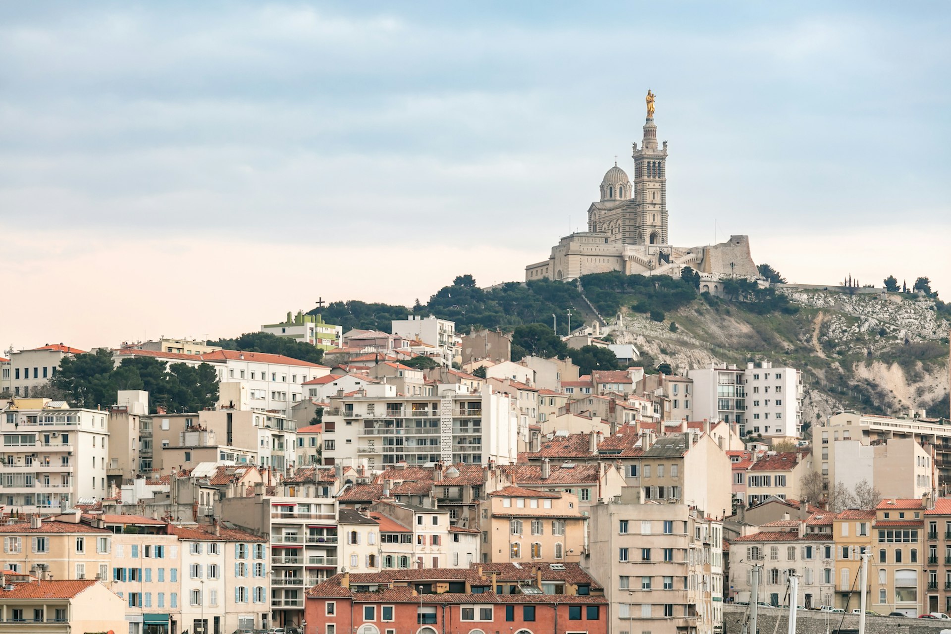 Buildings with Notre Dame de la Garde church on a hill in the distance, Marseille, France