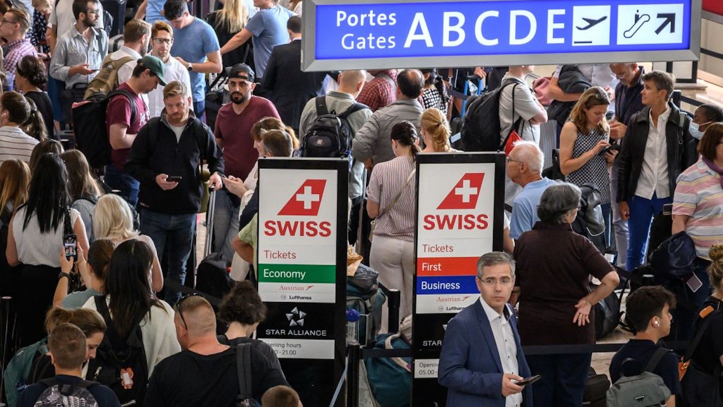 Travellers queue at Geneva Airport on June 15, 2022 after Swiss airspace was closed after a computer glitch with the air traffic control system grounded flights at the country's main airport. - Swiss airspace reopened on June 15, 2022 morning after a computer glitch grounded flights across the Alpine nation for several hours, officials said. (Photo by Fabrice COFFRINI / AFP) (Photo by FABRICE COFFRINI/AFP via Getty Images)