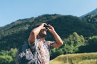 Young male hiker looking up through binoculars, Primaluna, Trentino-Alto Adige, Italy