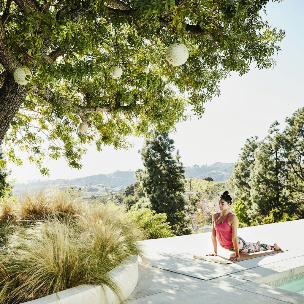 Woman performing yoga on pool deck of home