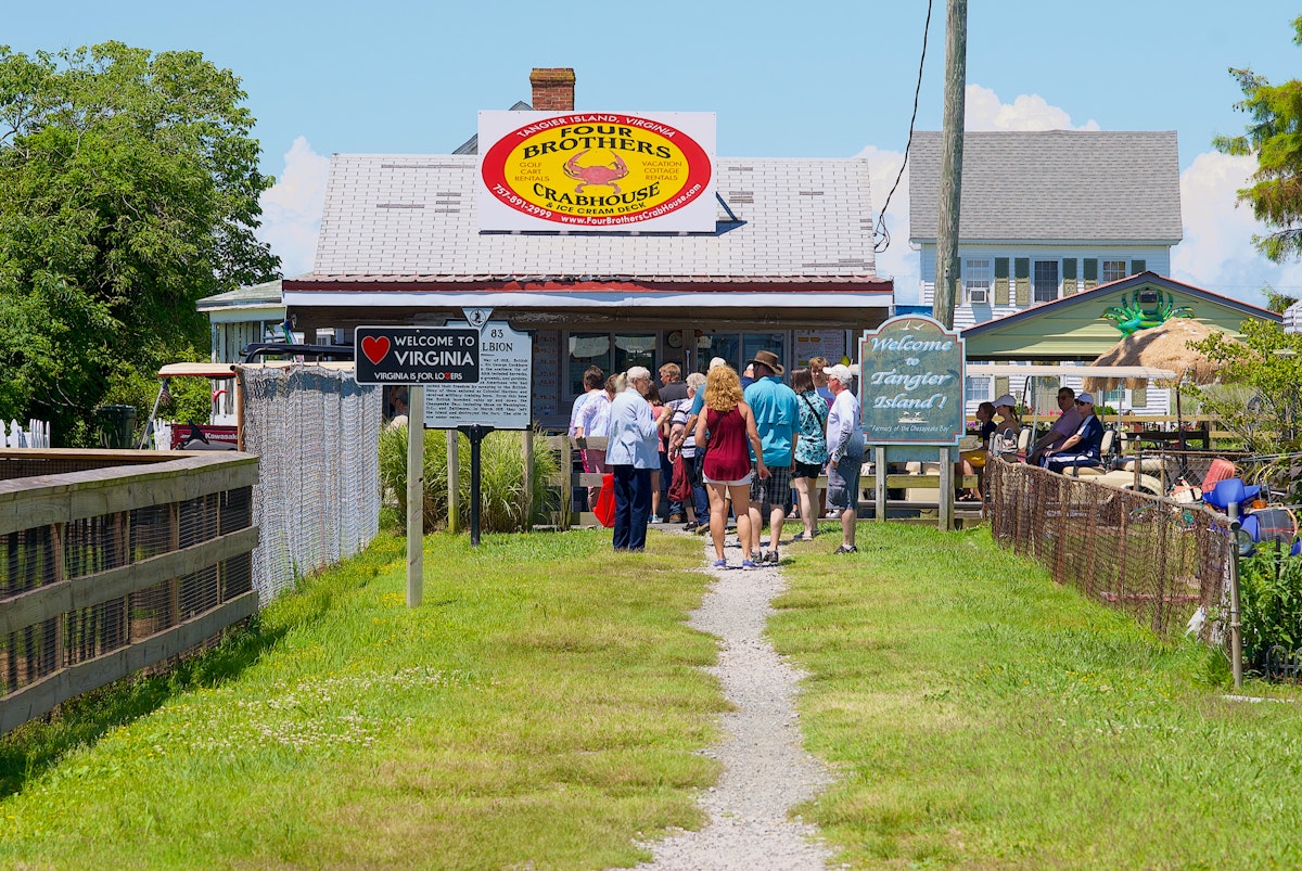 Visitors walk past the “Welcome to Virginia” and “Welcome to Tangier Island!” signs on their way to Main Street on Tangier Island.