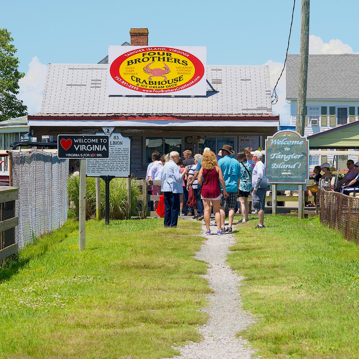 Visitors walk past the “Welcome to Virginia” and “Welcome to Tangier Island!” signs on their way to Main Street on Tangier Island.
