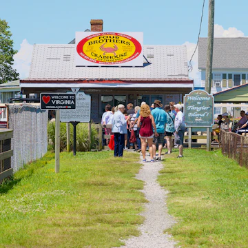 Visitors walk past the “Welcome to Virginia” and “Welcome to Tangier Island!” signs on their way to Main Street on Tangier Island.