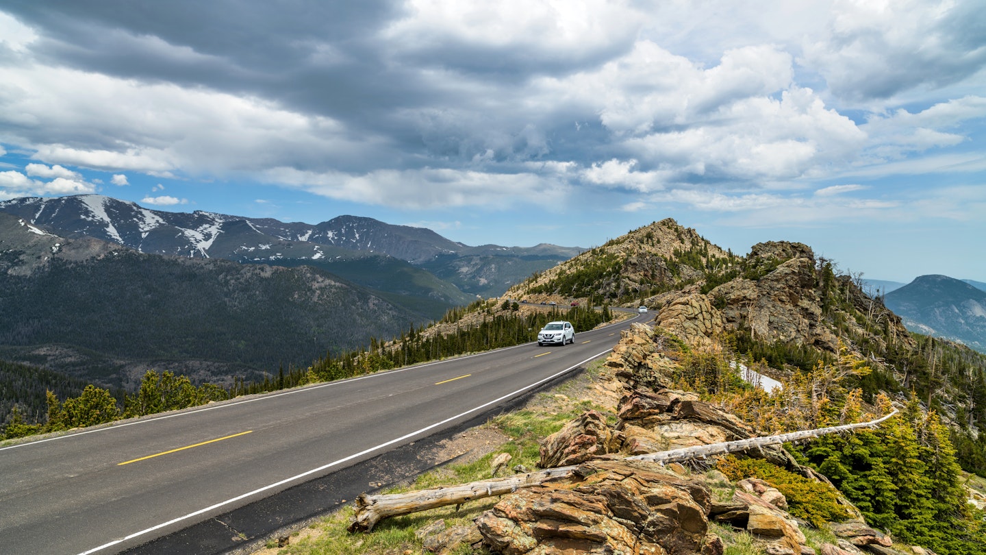 Estes Park, Colorado, USA - June 3, 2018: Cars are driving through a narrow section of Trail Ridge Road winding at top of mountains in Rocky Mountain National Park.