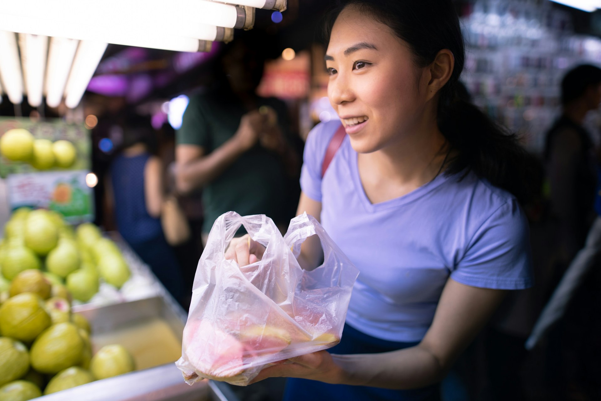 A smiling woman buys guava fruit at a street market, Taiwan