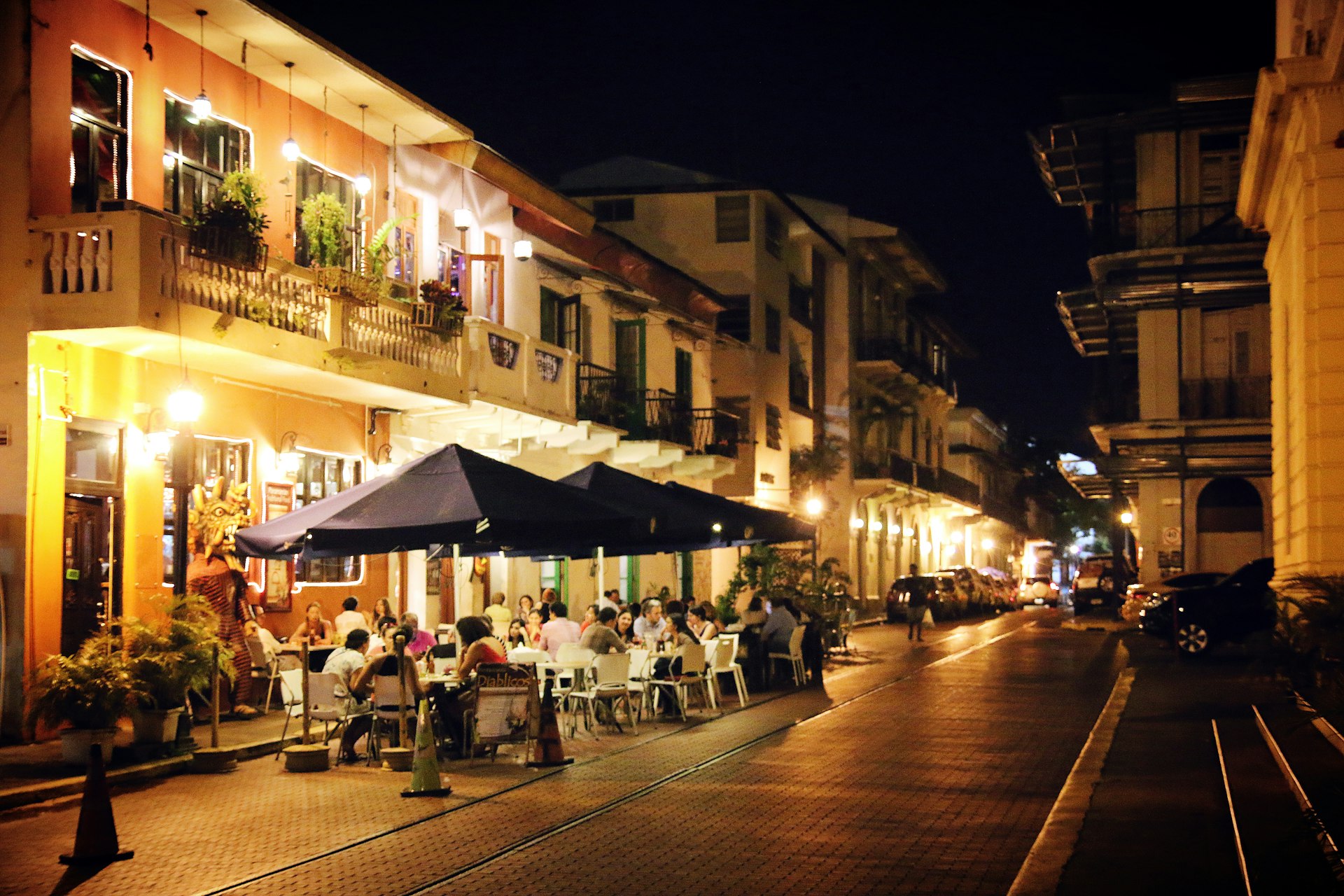People at night, dining at outdoor tables with umbrellas in the quaint and historic surroundings along the streets of Panama's old quarter