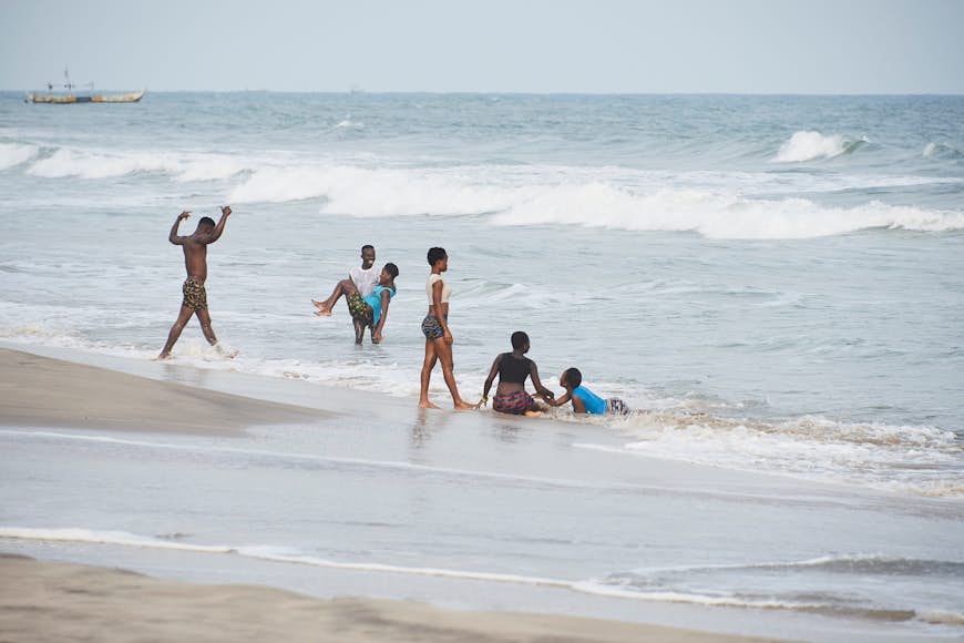 En grupp ungdomar plaskar i vattnet i Atlanten vid Kokrobite Beach, Accra, Ghana