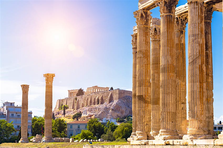 Zeus temple overlooking Acropolis, Athens, Greece. These are famous landmarks of Athens. Sunny view of Ancient Greek ruins, great columns of classical building in Athens city center.