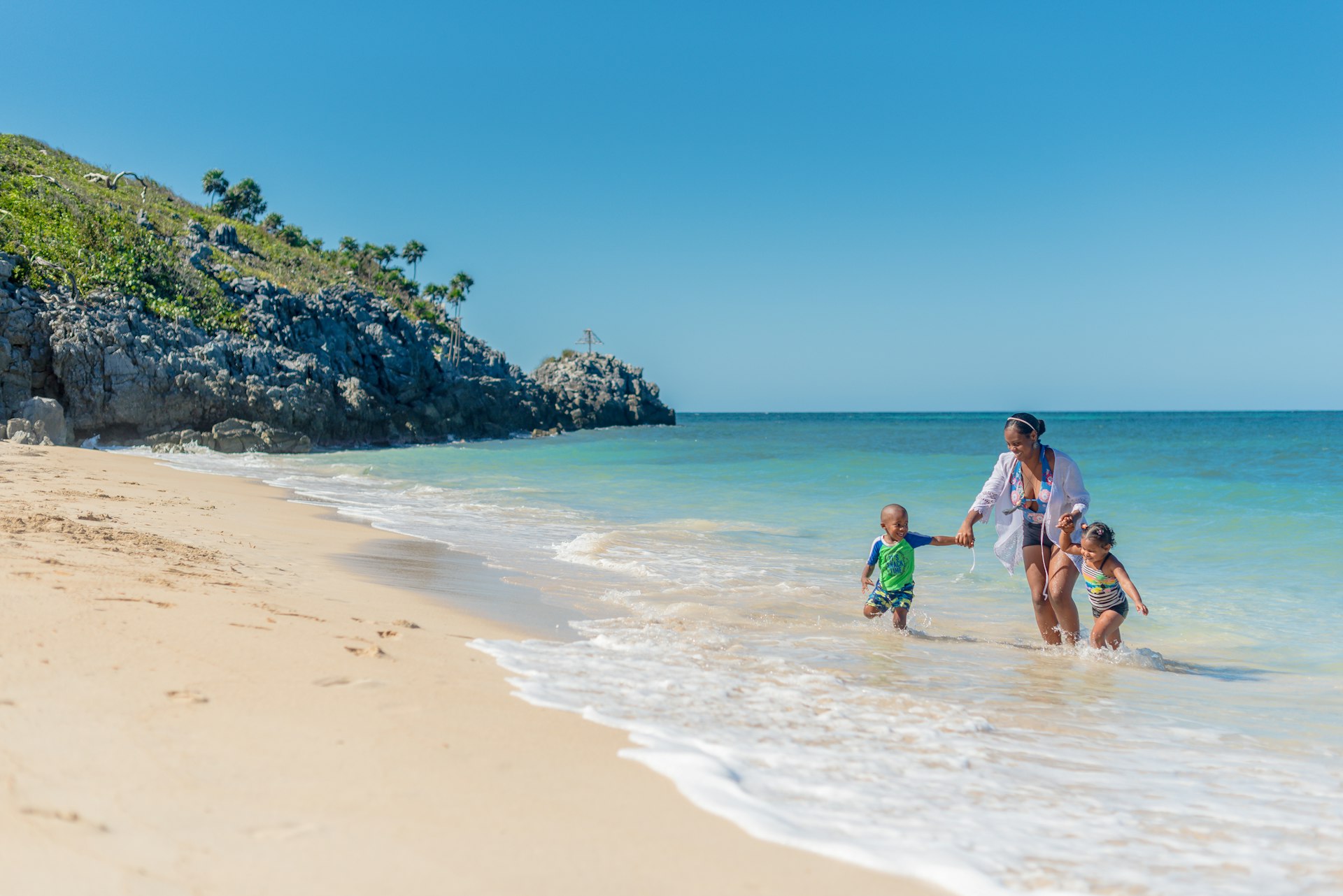 A family enjoying the beach at the Paya Bay Resort on ǲá, Honduras