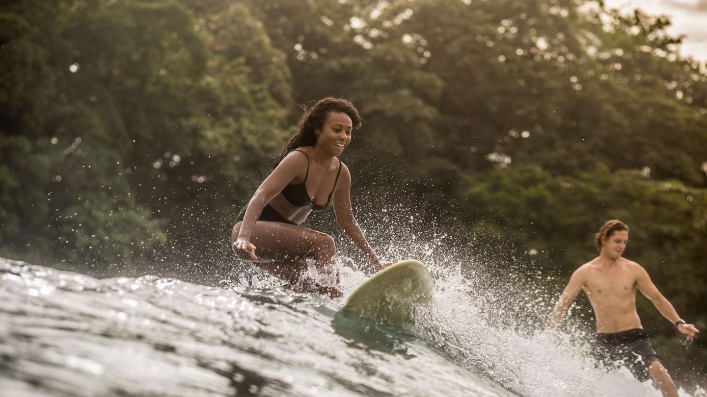 Indonesia, Java, happy woman and man surfing - stock photo