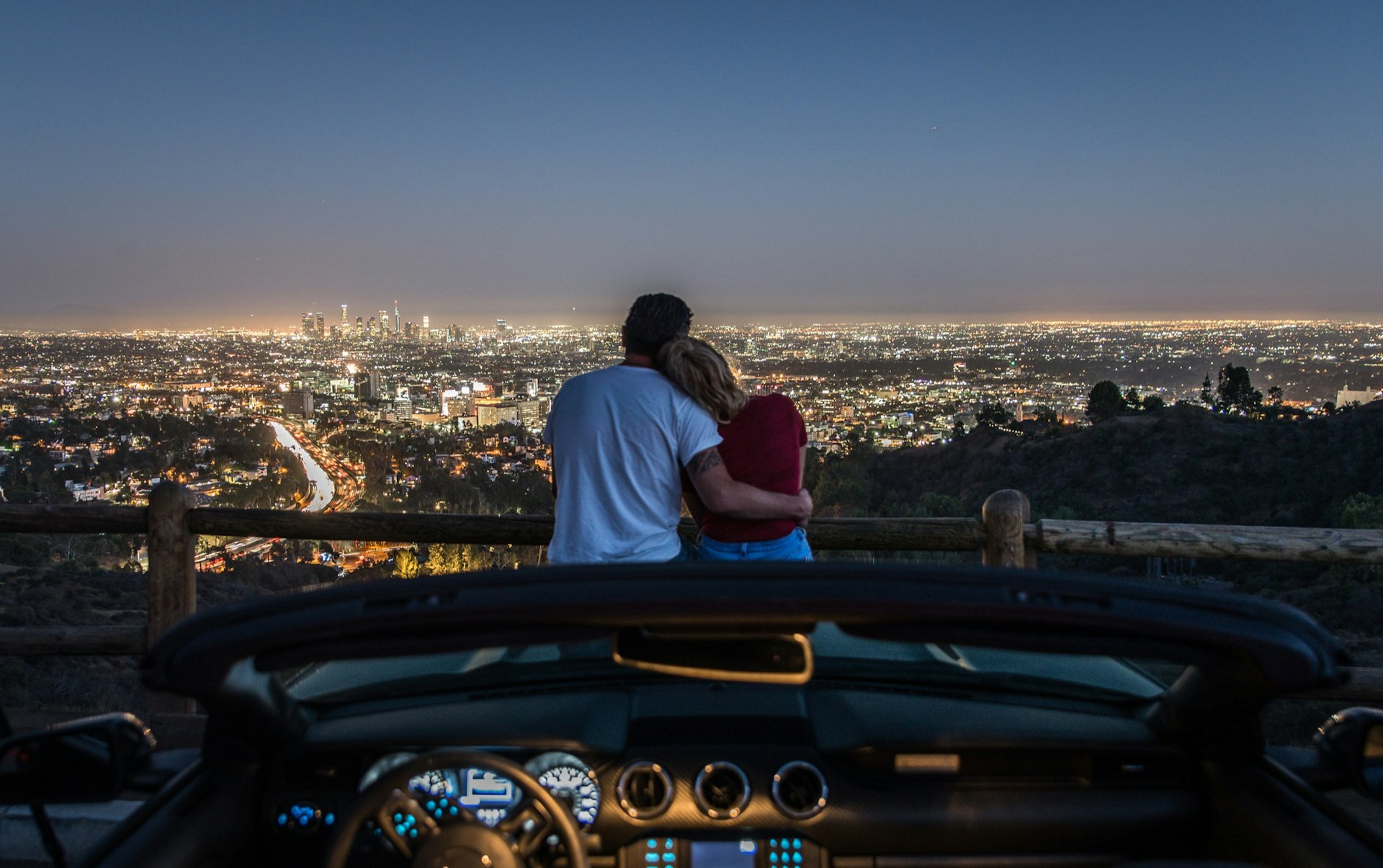 Couple,Enjoying,Skyline,View,From,Their,Car,In,The,Night.