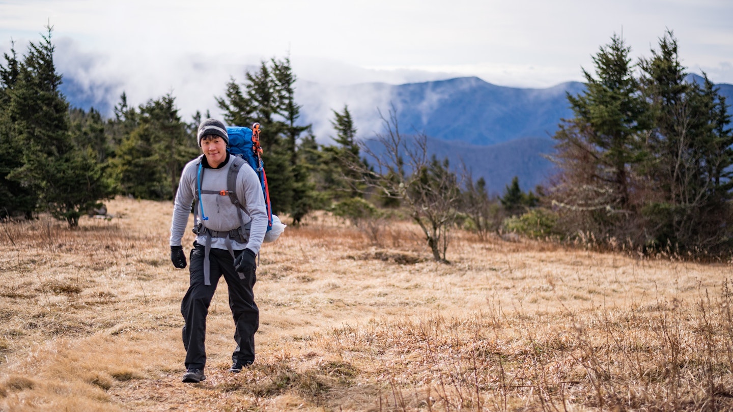 A man wearing a large backpack hikes in the woods in North Carolina. 
