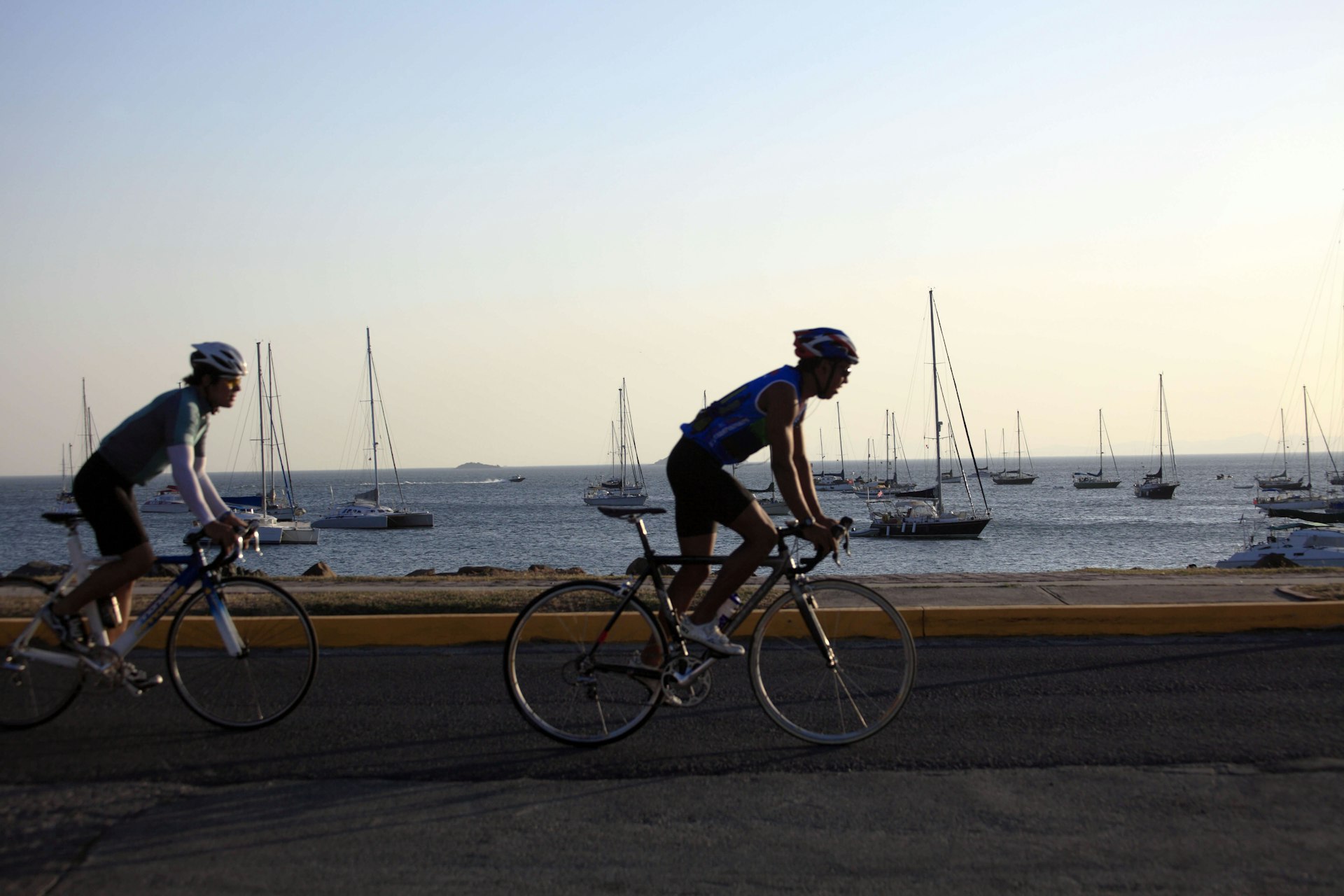 Two cyclists on Amador Causeway at sunset