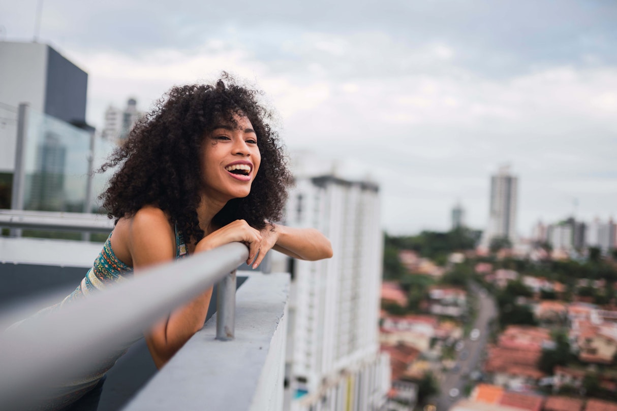 Panama, Panama City, portrait of happy young woman on balcony - stock photo