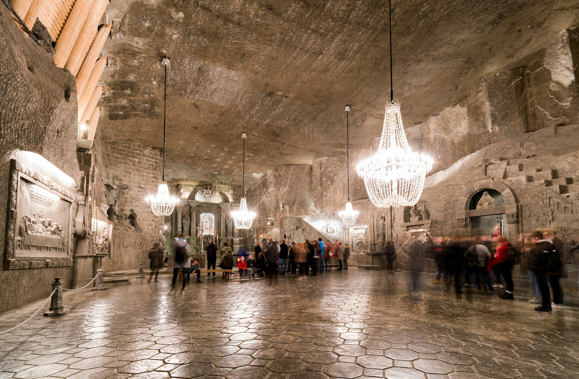 The main chamber in a vast salt mine, with chandeliers hanging down and people moving around
