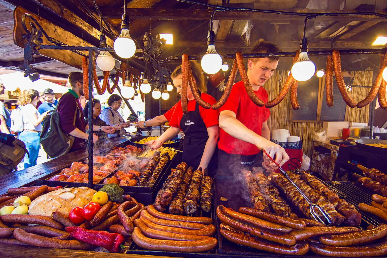 Two people cook sausages at a street-food stall in Krakow