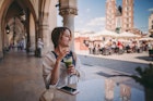 Relaxed woman at cafe drinking green smoothie and enjoying the old town of Krakow