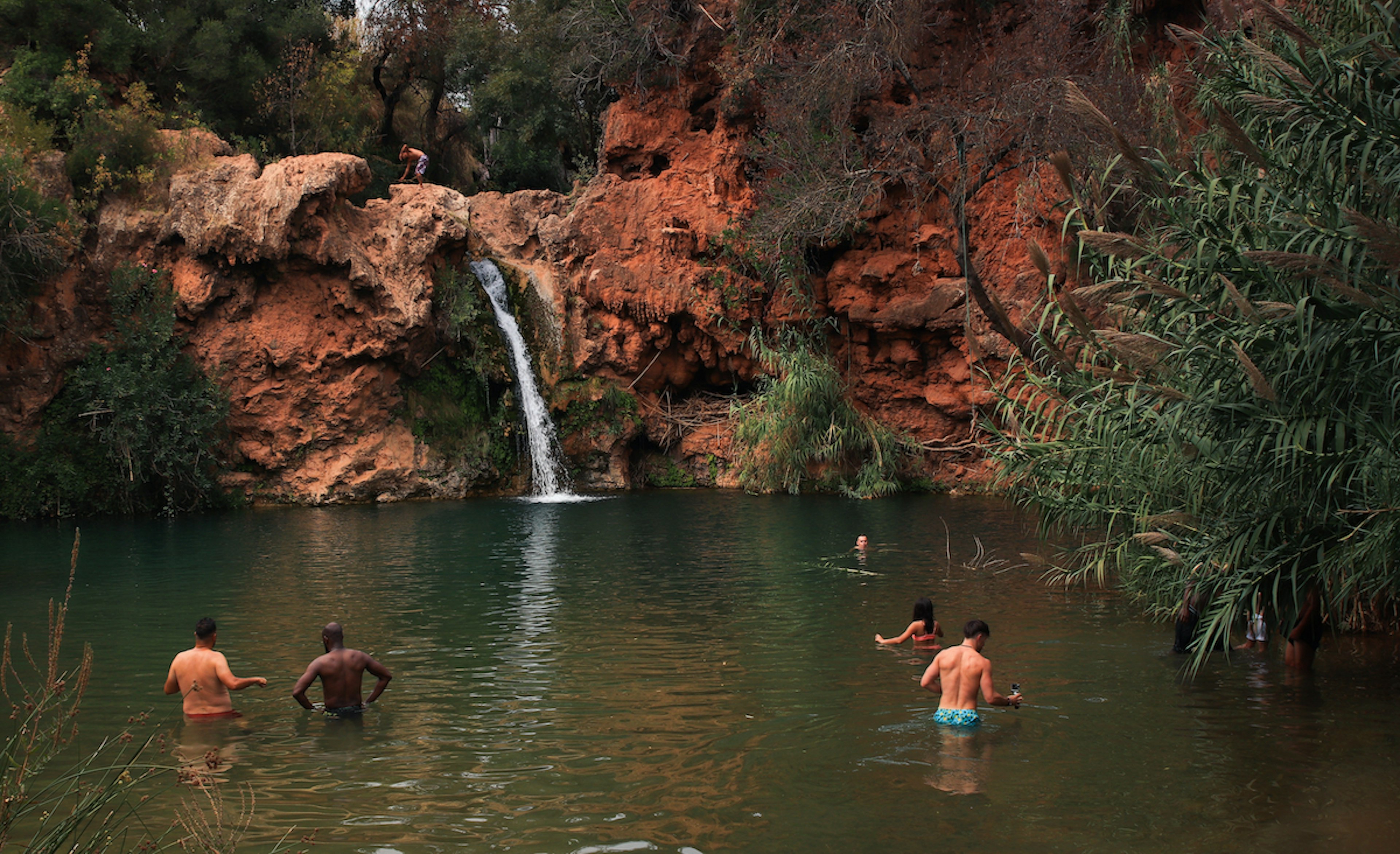 People wade in the water at Cascata do Pego do Inferno, the Algarve, Portugal