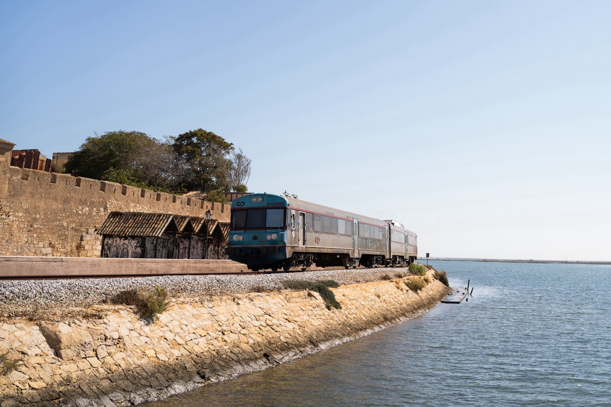 Train crossing the coast path on the shore of the Atlantic ocean in Faro, Algarve, Portugal; Shutterstock ID 1813158679; your: Brian Healy; gl: 65050; netsuite: Lonely Planet Online Editorial; full: Getting around the Algarve