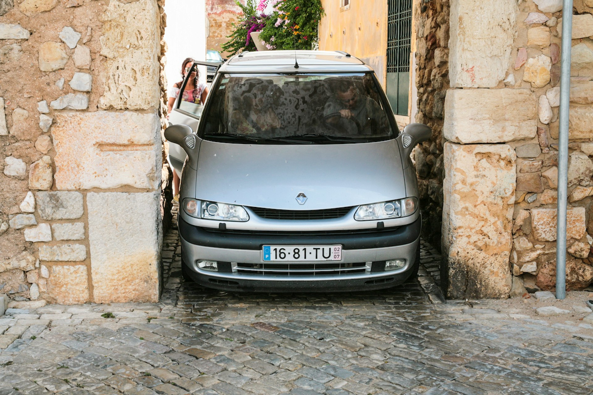 A car is tightly parked in a narrow medieval gateway in the old town of Faro, the Algarve, Portugal