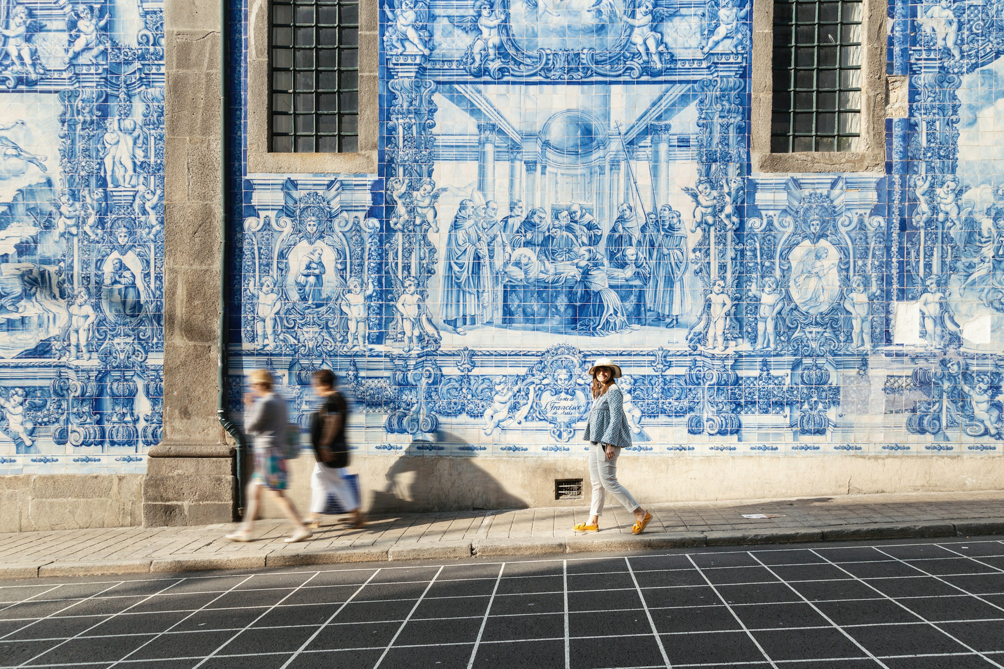 Woman walking in Porto against azulejos wall. Capela das Almas church, Portugal, Europe