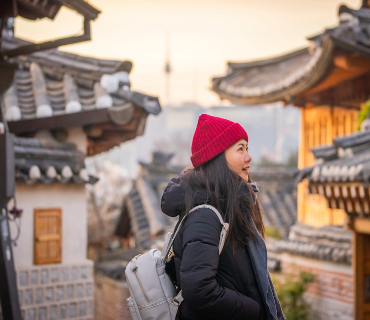 Casual Portrait of Smiling Young Asian Tourist at Traditional Bukchon Hanok Village in Winter at Sunrise, Seoul, Korea; Shutterstock ID 1376673824; your: Brian Healy; gl: 65050; netsuite: Lonely Planet Online Editorial; full: Best neighborhoods in Seoul