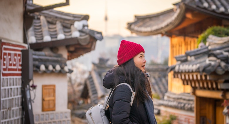 Casual Portrait of Smiling Young Asian Tourist at Traditional Bukchon Hanok Village in Winter at Sunrise, Seoul, Korea; Shutterstock ID 1376673824; your: Brian Healy; gl: 65050; netsuite: Lonely Planet Online Editorial; full: Best neighborhoods in Seoul