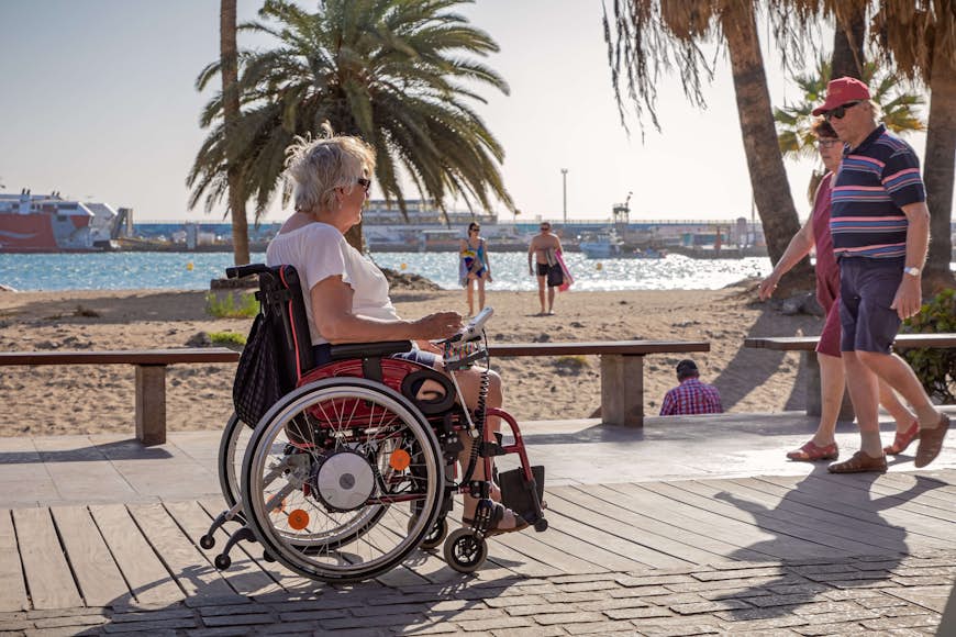 Женщина в электрической инвалидной коляске наслаждается пляжем
