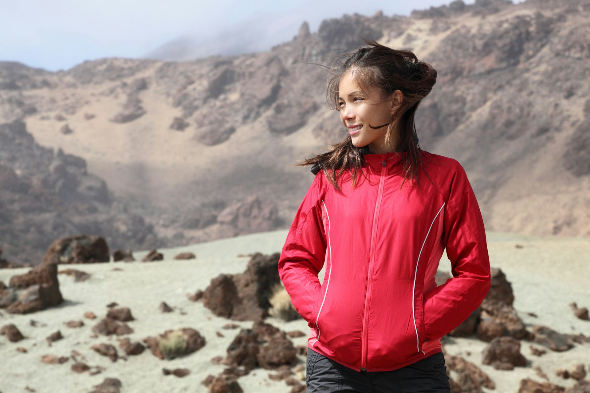 Hiking outdoors person looking at copy space to the side. Asian Caucasian female model. From volcano landscape on Teide, Tenerife, Canary Islands, Spai