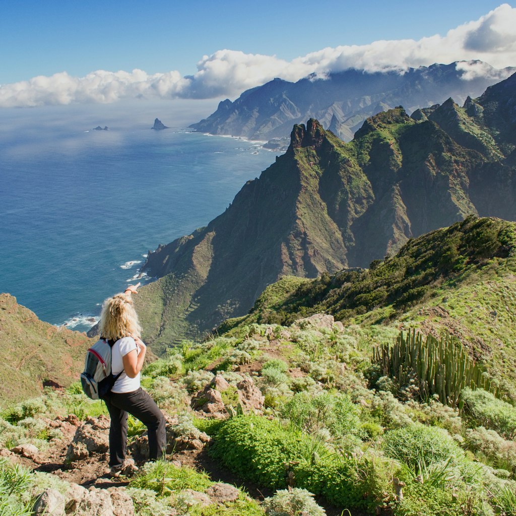 Woman hiker watching beautiful costal scenery. - Tenerife, Canary Islands,  Spain. Western coast view, mountain Anaga  and Atlantic ocean