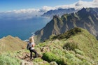 Woman hiker watching beautiful costal scenery. - Tenerife, Canary Islands,  Spain. Western coast view, mountain Anaga  and Atlantic ocean