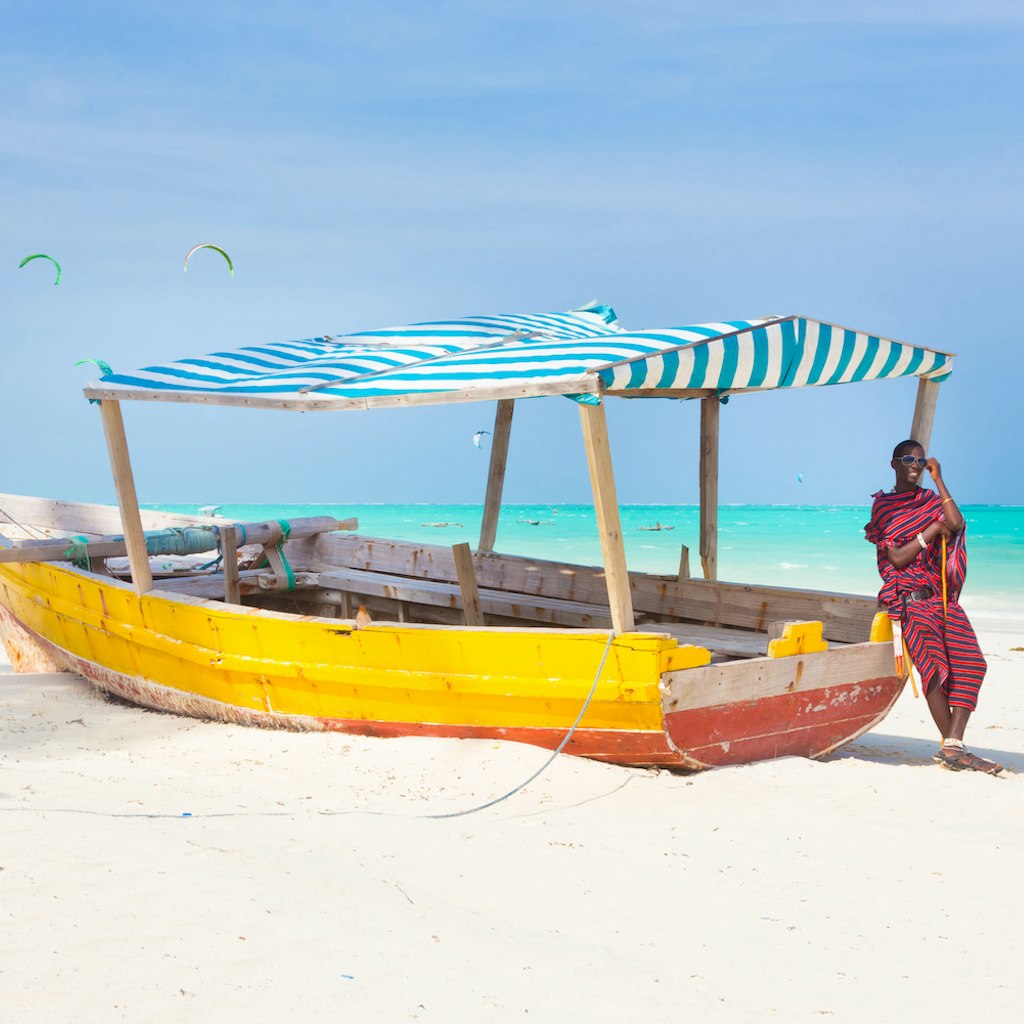 Maasai warrior lounging aroundon traditional colorful wooden boat on picture perfect tropical sandy beach on Zanzibar, Tanzania, East Africa. Kiteboarding spot on Paje beach.; Shutterstock ID 256650787; your: Brian Healy; gl: 65050; netsuite: Lonely Planet Online Editorial; full: Best things to do in Tanzania