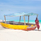 Maasai warrior lounging aroundon traditional colorful wooden boat on picture perfect tropical sandy beach on Zanzibar, Tanzania, East Africa. Kiteboarding spot on Paje beach.; Shutterstock ID 256650787; your: Brian Healy; gl: 65050; netsuite: Lonely Planet Online Editorial; full: Best things to do in Tanzania