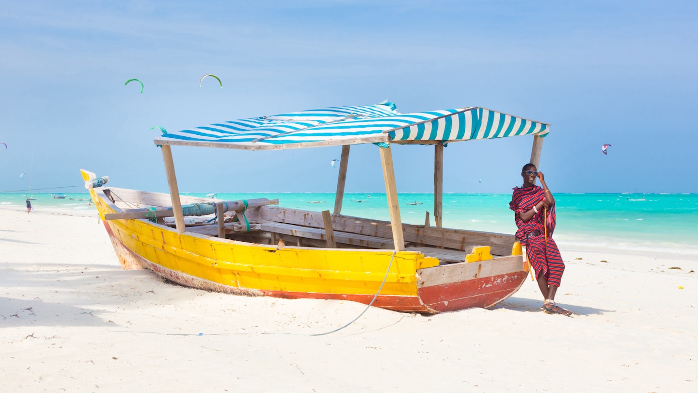 Maasai warrior lounging aroundon traditional colorful wooden boat on picture perfect tropical sandy beach on Zanzibar, Tanzania, East Africa. Kiteboarding spot on Paje beach.; Shutterstock ID 256650787; your: Brian Healy; gl: 65050; netsuite: Lonely Planet Online Editorial; full: Best things to do in Tanzania