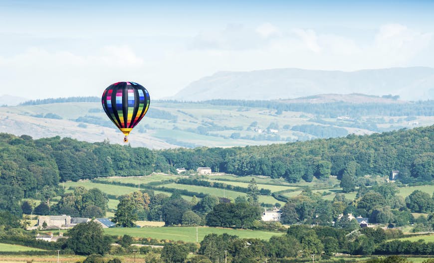 Un ballon à air chaud coloré flotte au-dessus de la verte campagne de Cumbria, Angleterre, RU