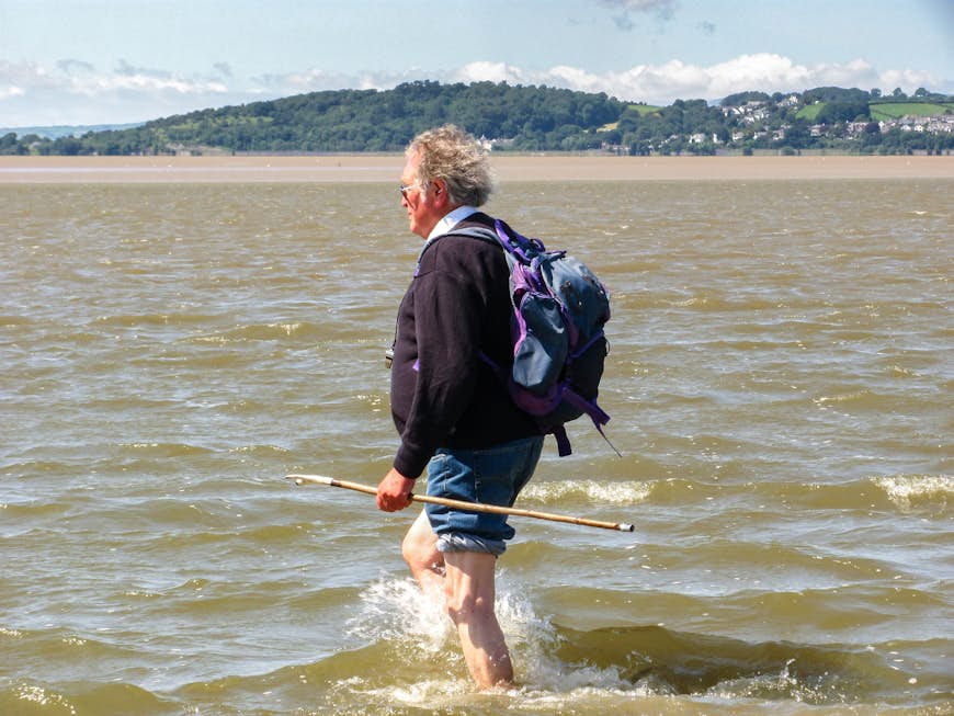 A man wades into Morecambe Bay between Far Arnside and Grange-over-Sands, Cumbria, England, United Kingdom