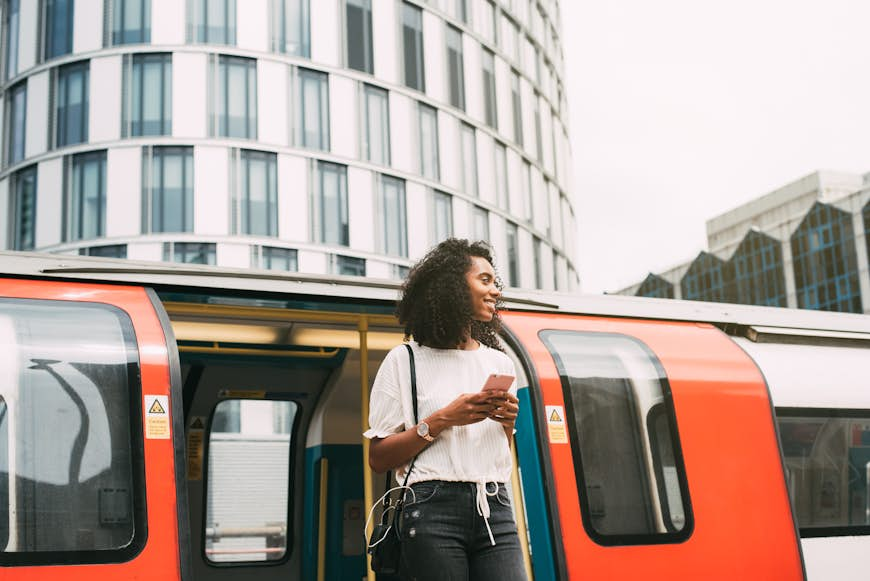 A woman exiting the London Tube holding her phone