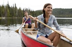 A couple smile while canoeing on a lake.