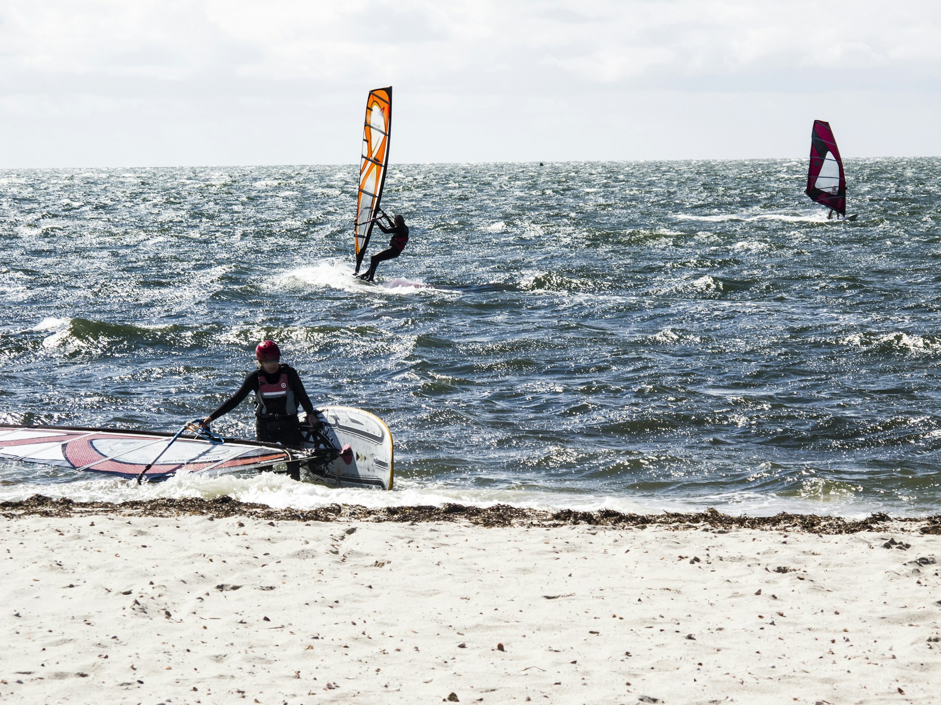 Windsurfers out on the water as one comes in to the shore