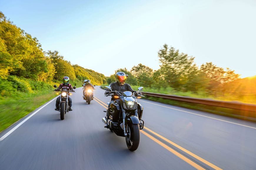 Close landscape of motorcyclists on the Cherohala Skyway at sunset with foliage in background. Taken under clear blue sky