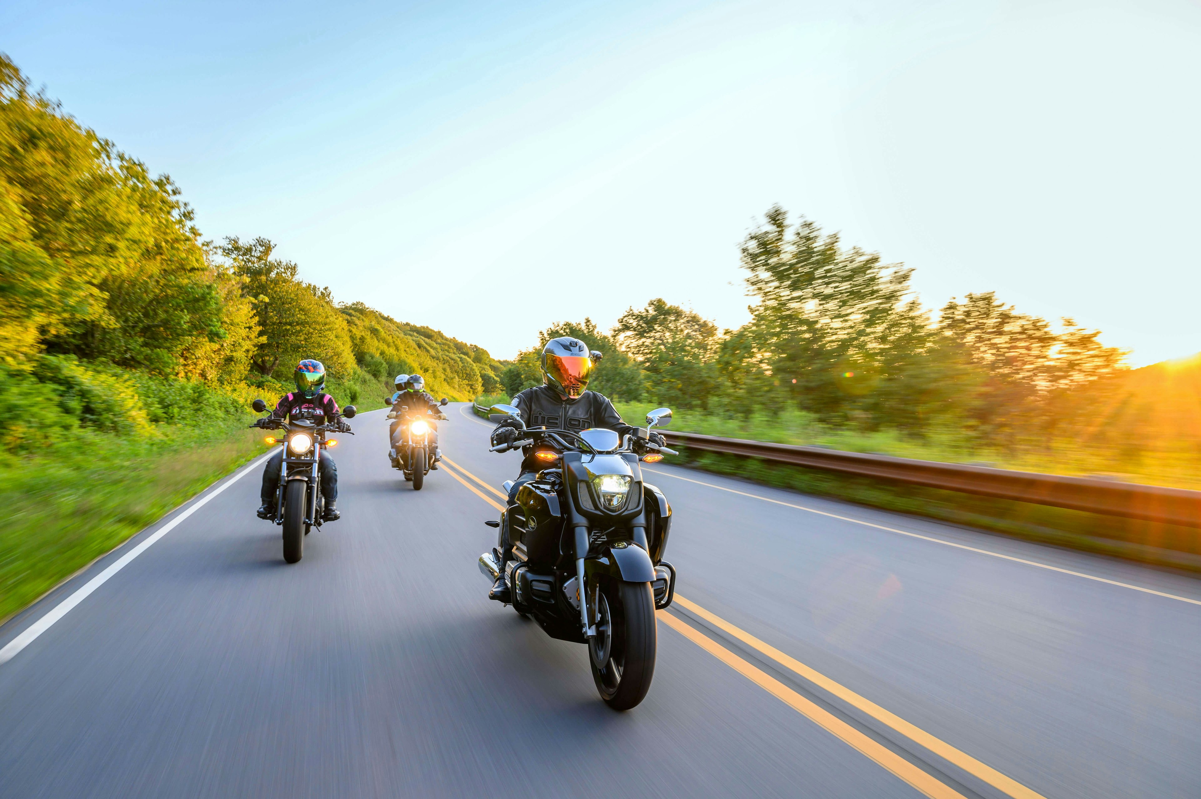 Close landscape of motorcyclists on the Cherohala Skyway at sunset with foliage in background. Taken under clear blue sky