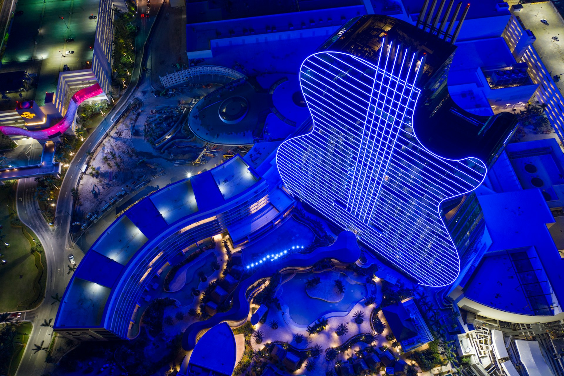 An aerial drone photo of the guitar-shaped Seminole Hard Rock Hotel & Casino illuminated in blue lights at night, Seminole, Florida, USA