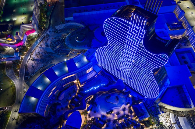 An aerial drone photo of the guitar-shaped Seminole Hard Rock Hotel & Casino illuminated in blue lights at night, Seminole, Florida, USA
