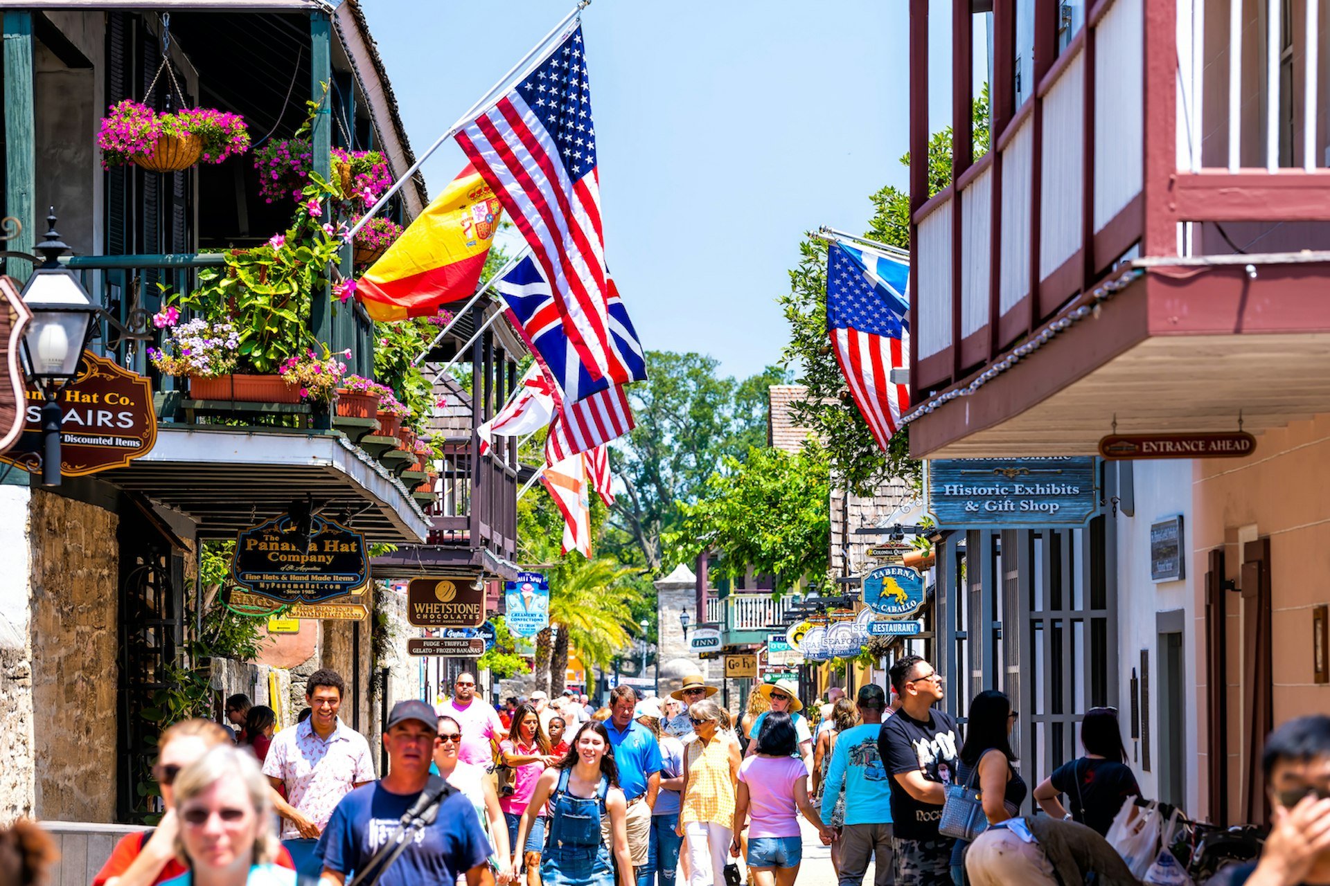 People shopping on St George St by stores, shops and restaurants American and international flags, St Augustine, Florida, USA